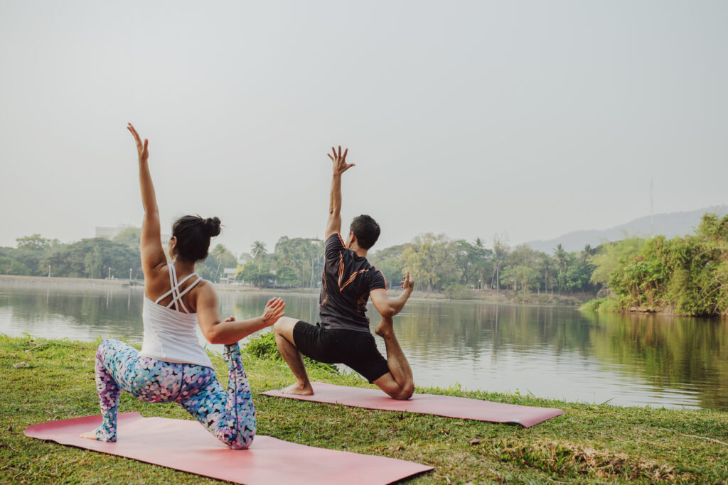 young couple doing yoga lake
